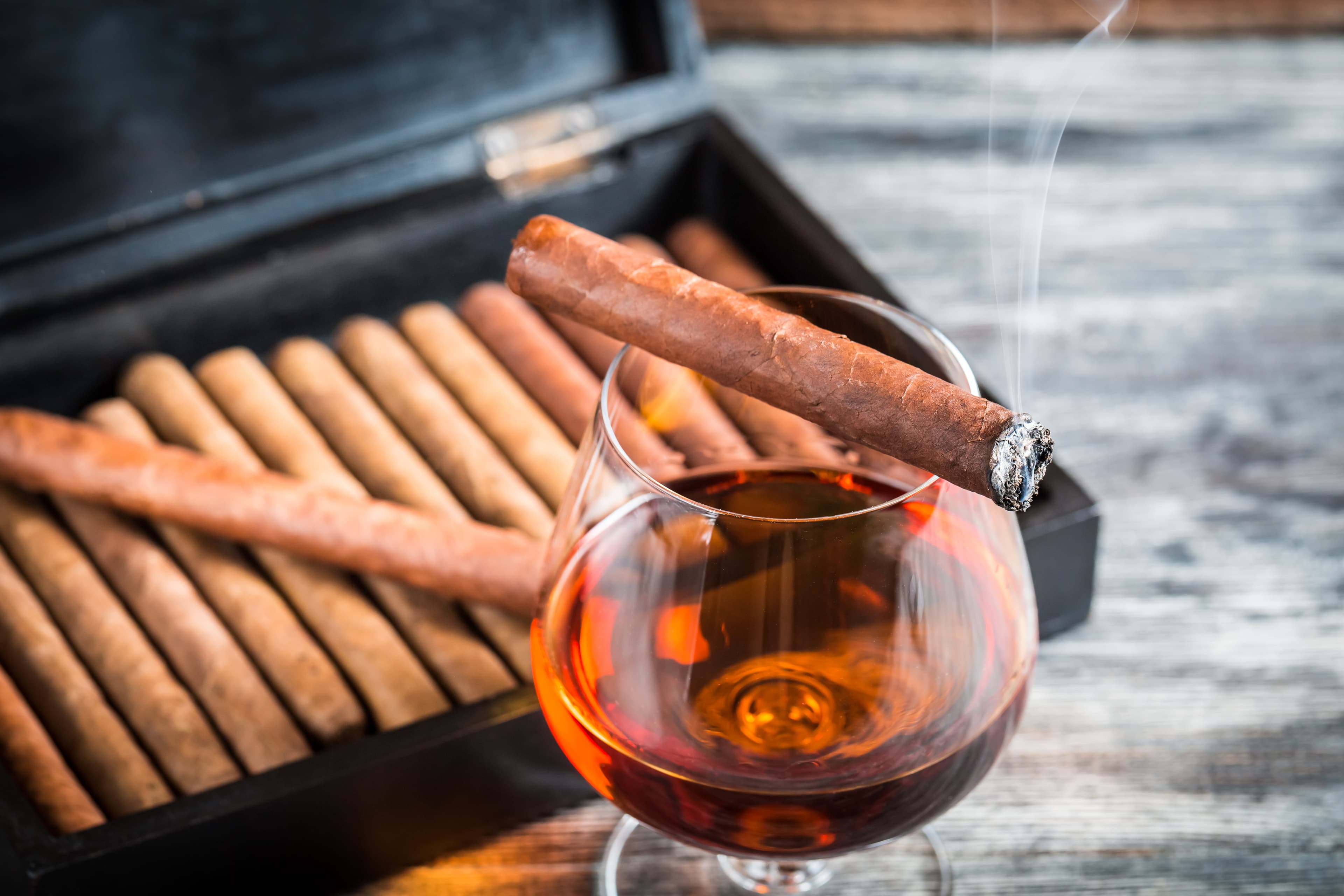 A cigar resting over a glass of cognac